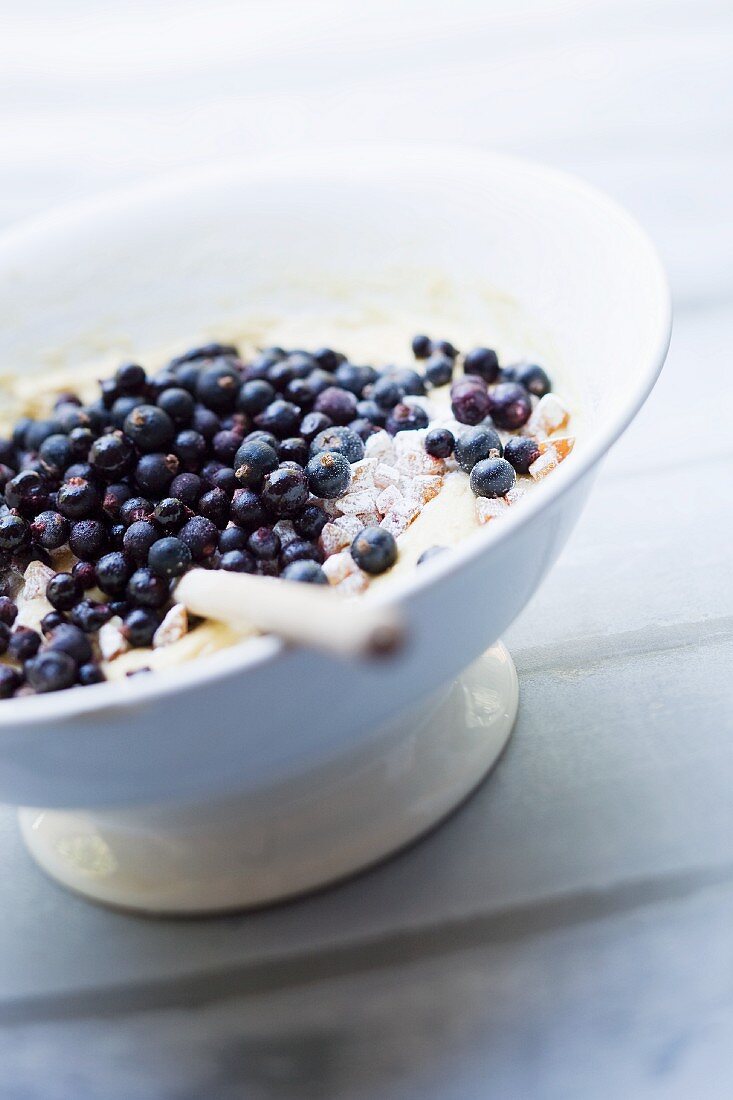 Kuchenteig mit scharzen Johannisbeeren in einer Schüssel