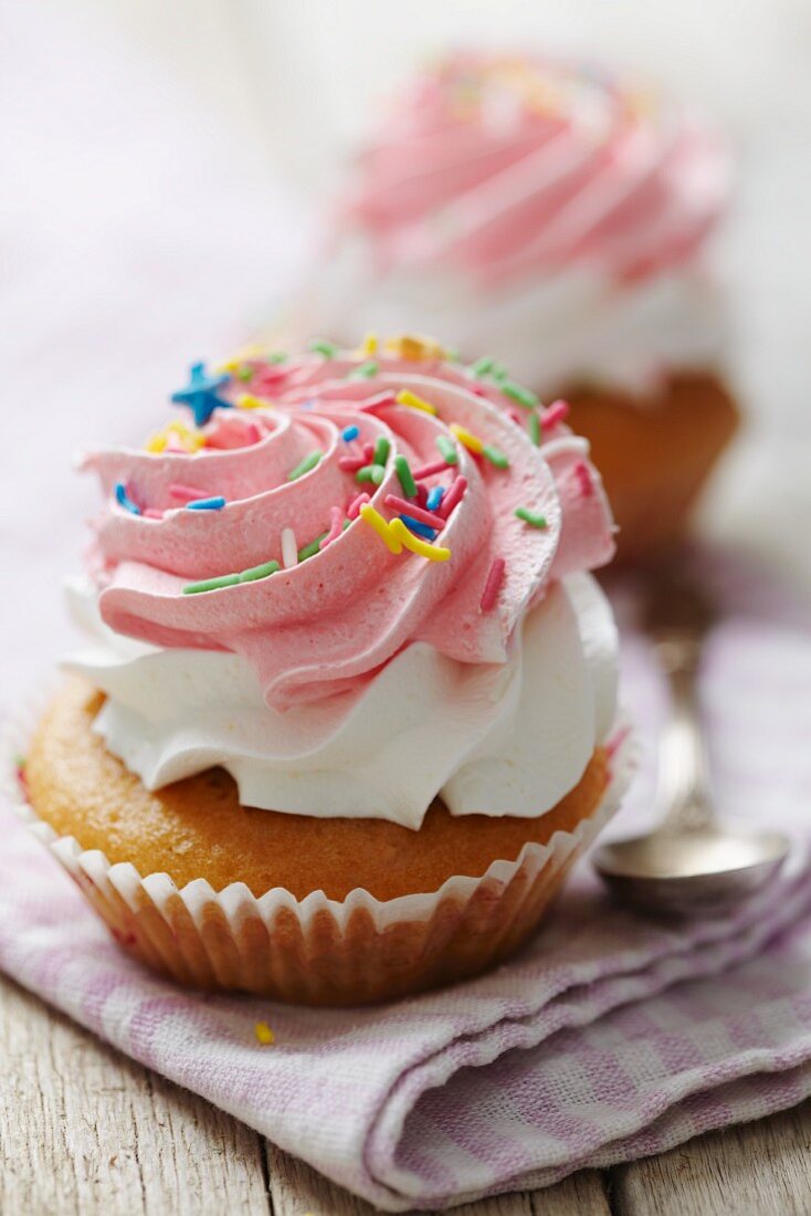 Cupcake mit Sahne, Himbeercreme und bunten Zuckerstreuseln