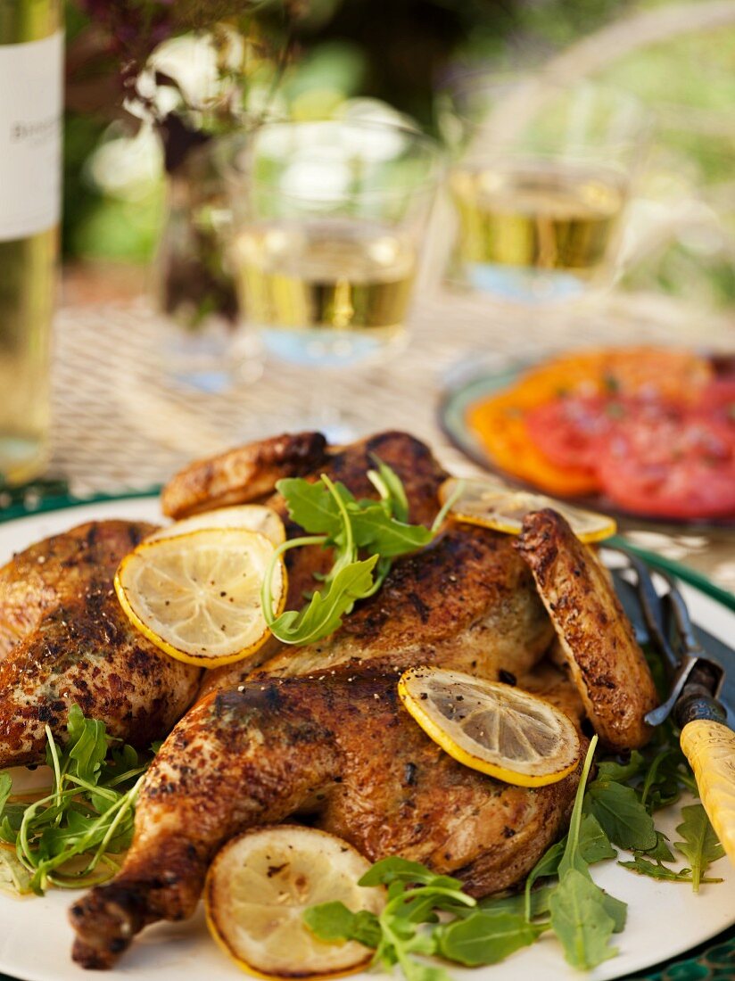 Grilled Butterflied Chicken with Lemon and Herbs on an Outdoor Table