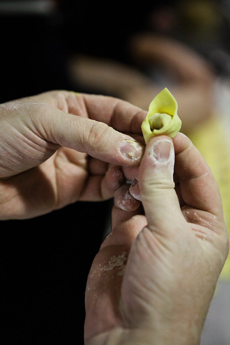Two hands shaping a tortellino