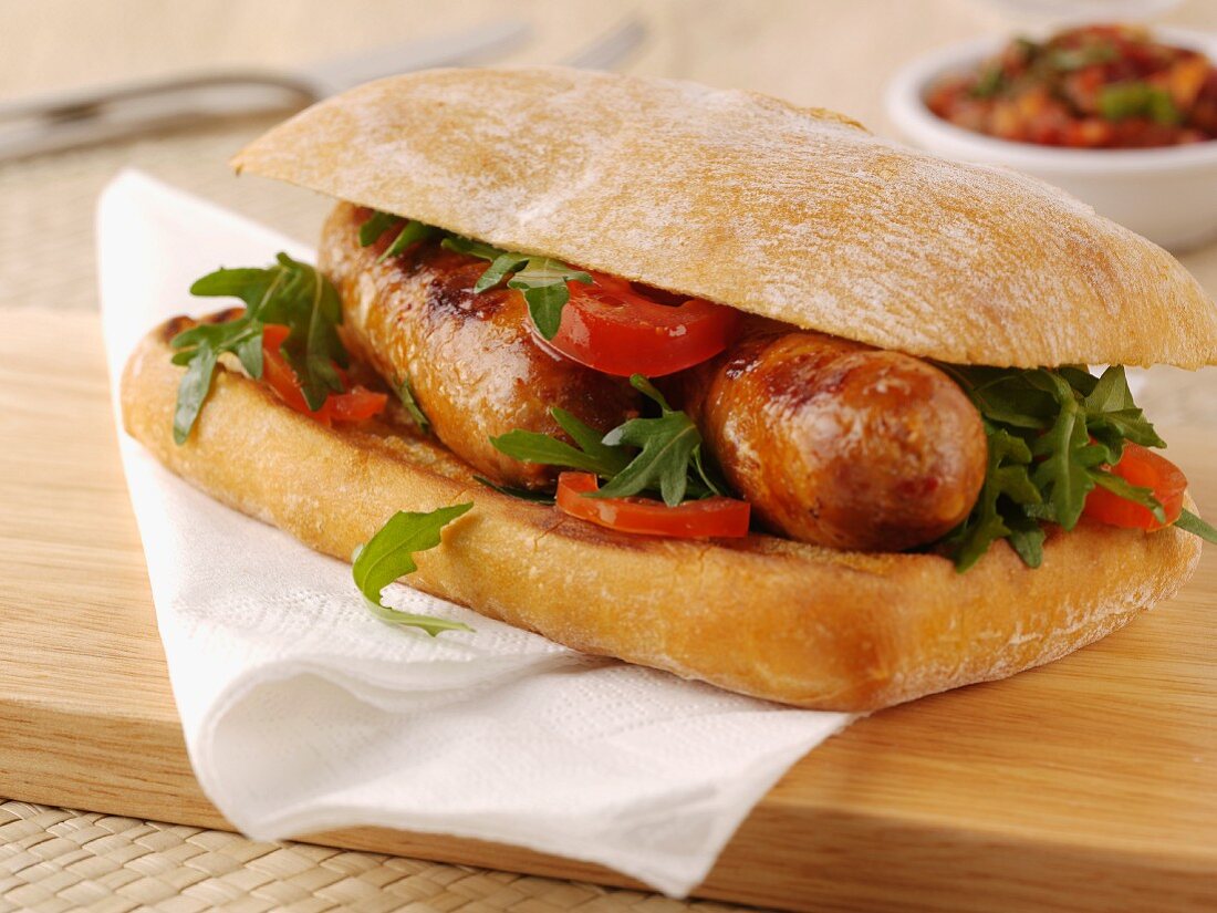 Ciabatta roll filled with sausages, tomato and rocket