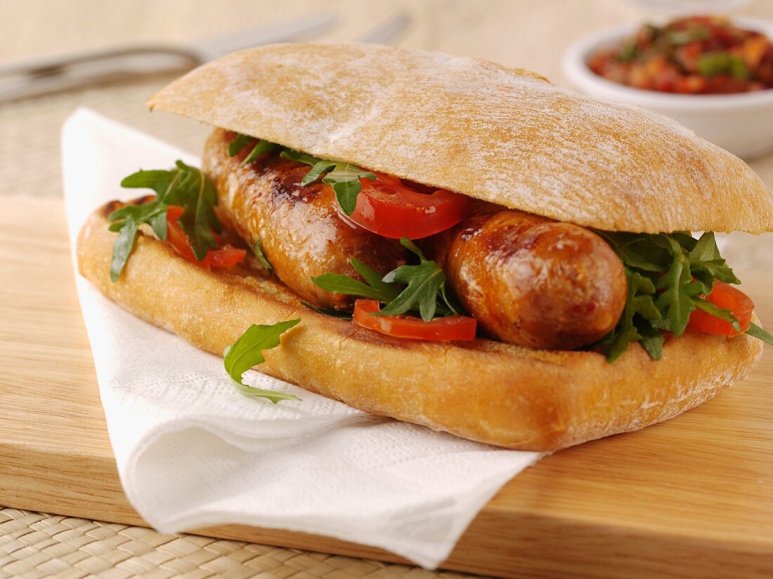 Ciabattabrötchen mit Bratwurst, Tomaten und Rucola