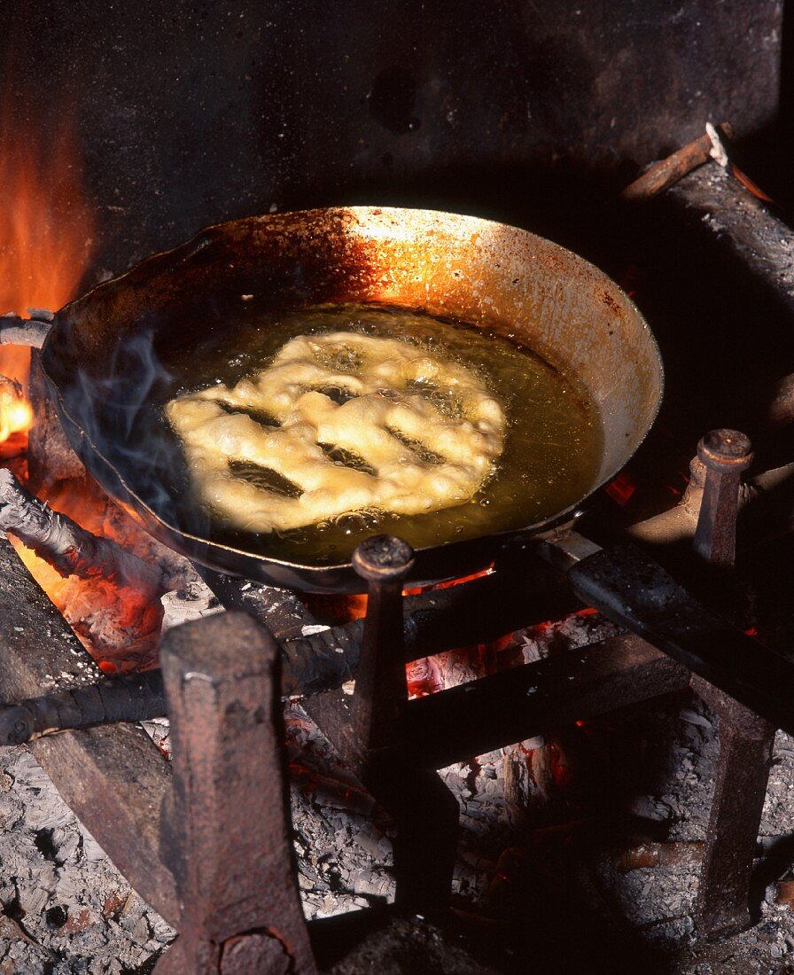 A fritter sizzling in olive oil