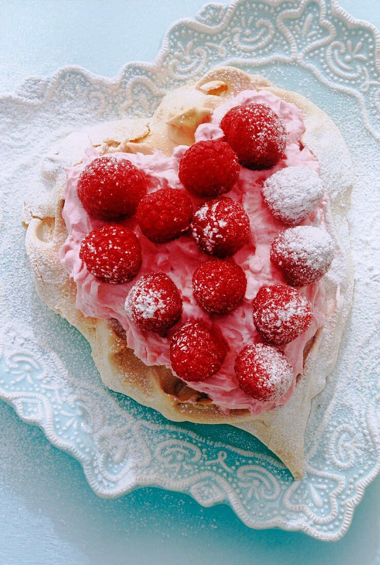 heart shaped meringue with cream and rasberries on heart shape plate