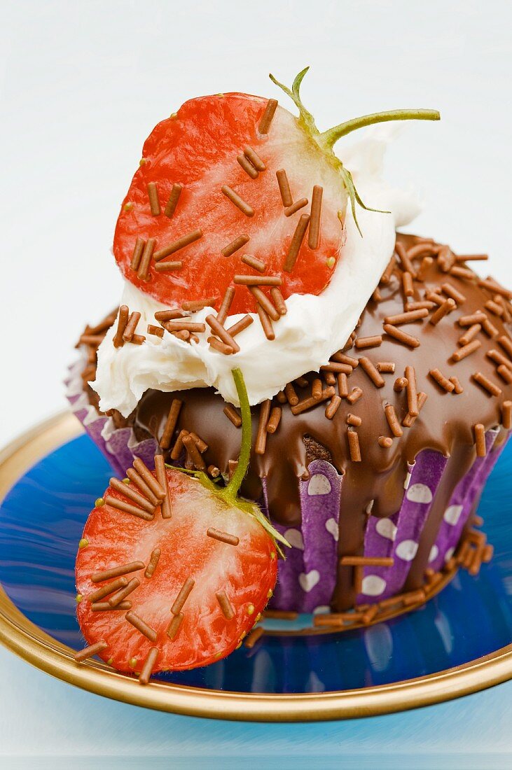 Cupcake mit Schokoglasur und halbierten frischen Erdbeeren