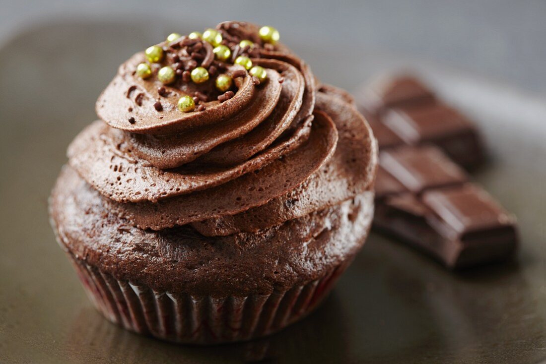A Single Chocolate Cupcake with Chocolate Frosting and White Sprinkles