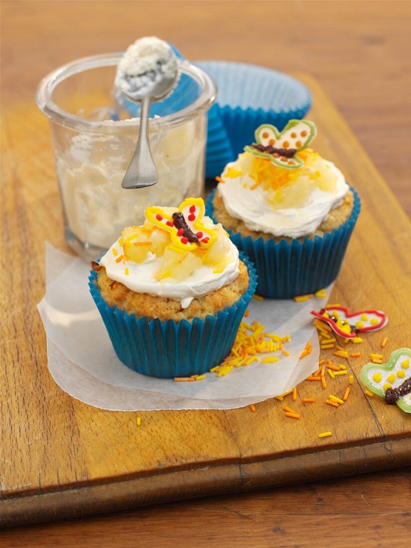 Cupcakes topped with pineapple and a butterfly decoration