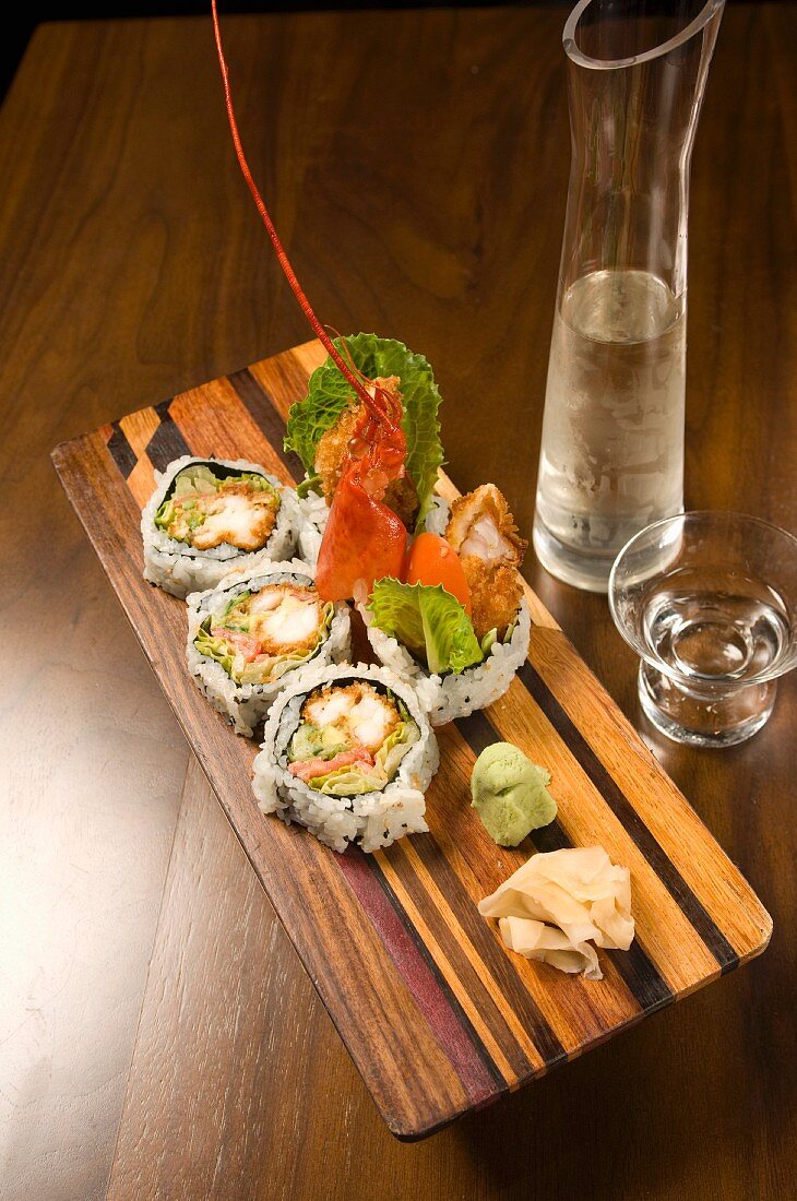 Hummer-Sushi auf einem Holzbrett, Krug und Glas Sake