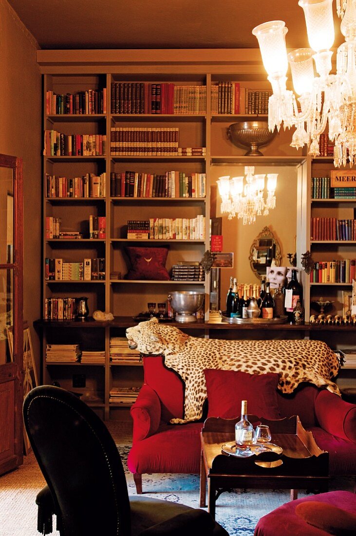 Grand library with integrated wall mirror, leopard skin on back of sofa and crystal chandelier