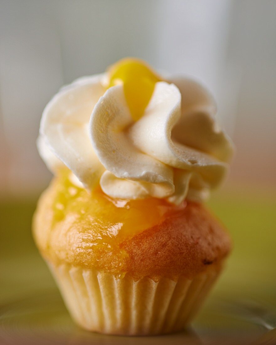 A cupcake topped with vanilla cream icing and lemon curd