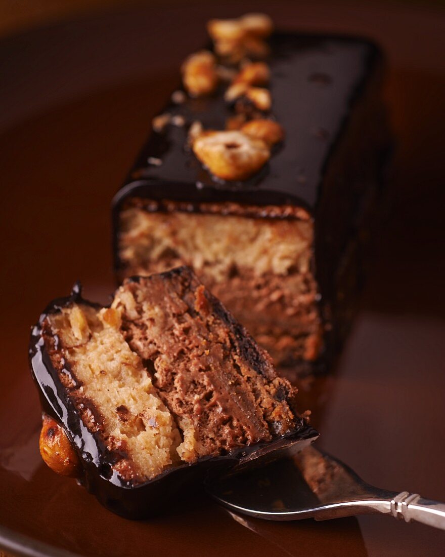 A chocolate cake with nuts, one slice cut