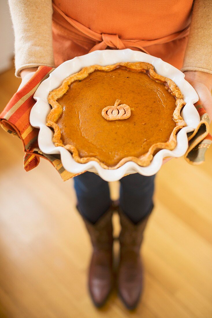 A woman holding a home-made pumpkin pie