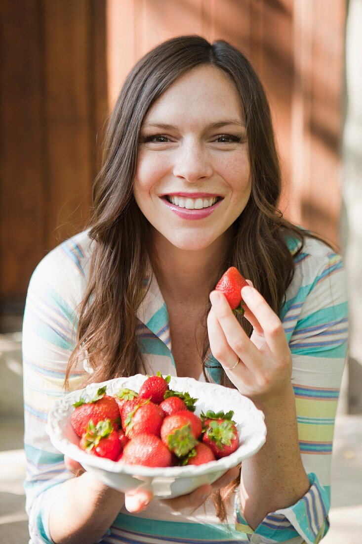 Junge Frau isst Erdbeeren