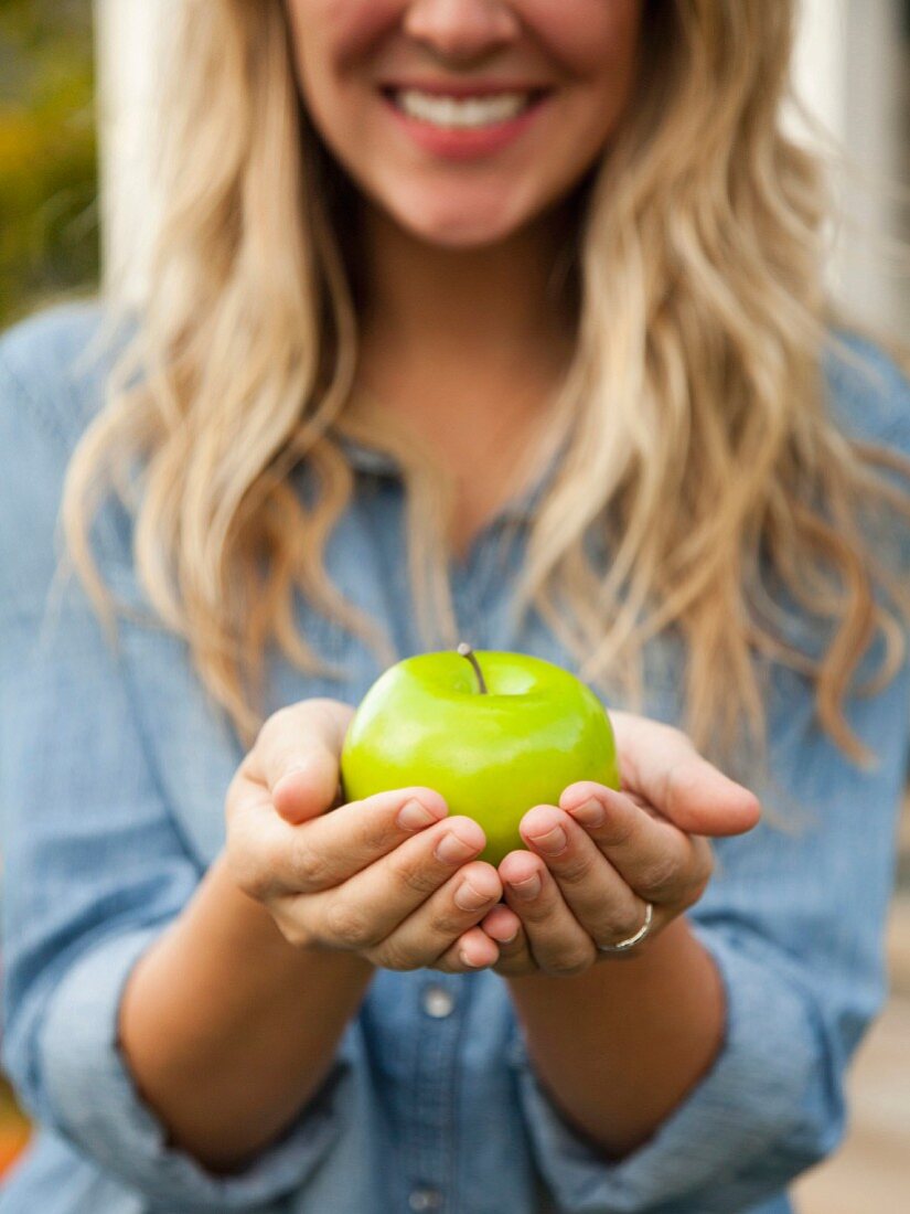 A blonde woman holding a green apple