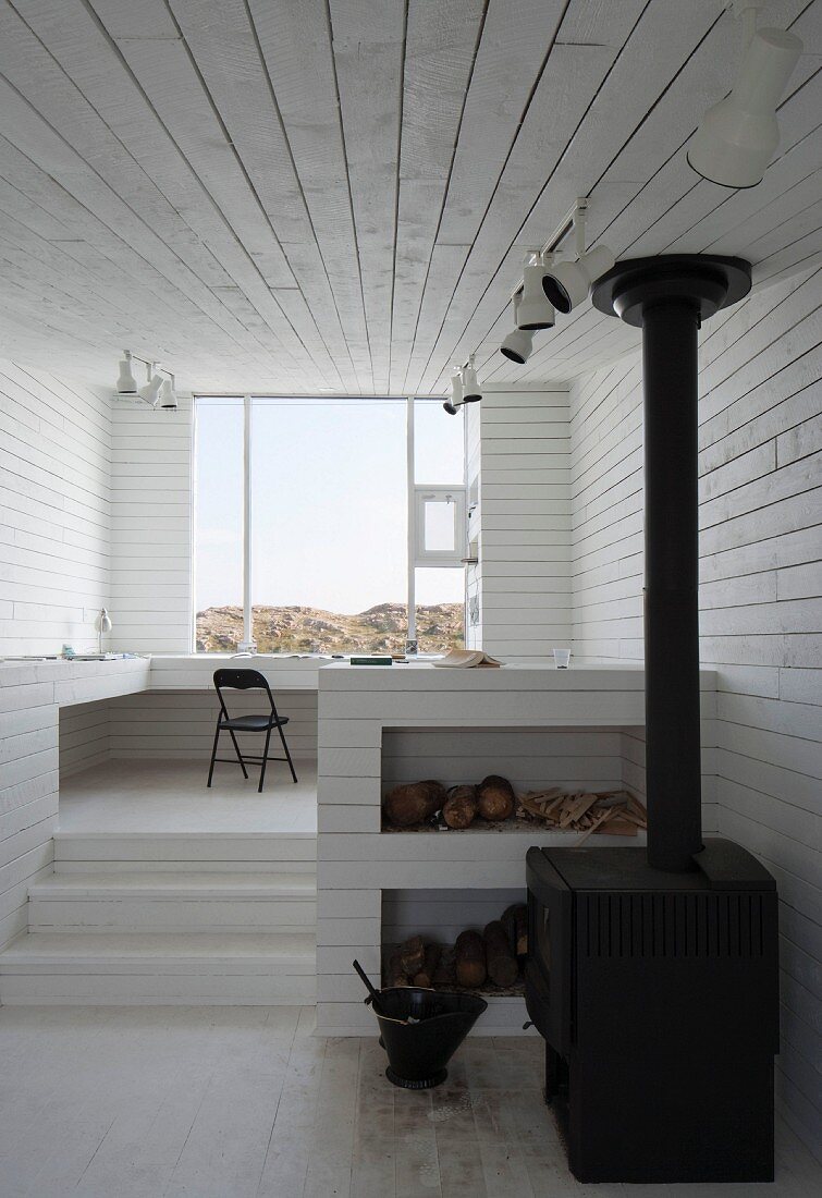 Innenraum mit weissen Holzwänden und Holzofen (Bridge Studio, Fogo Island, Kanada)