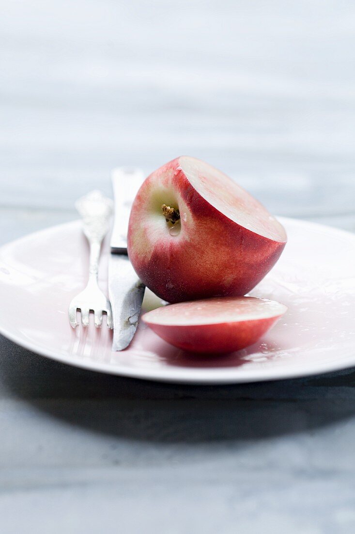 A nectarine, sliced open, on a plate