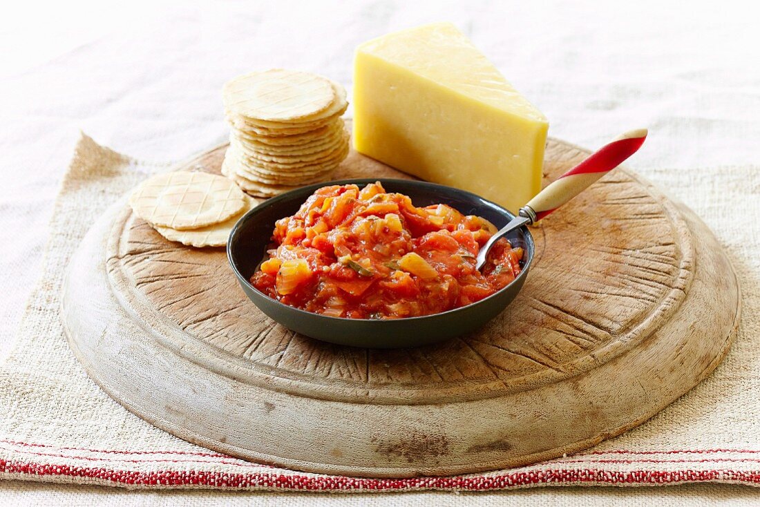 Scharfes Tomatenrelish mit Crackern & Käse auf Holzbrett