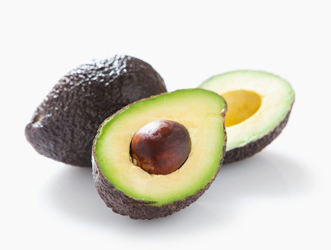 A whole and a halved avocado with no background