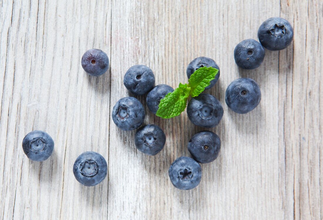 Blueberries and mint on a wooden slab, from above