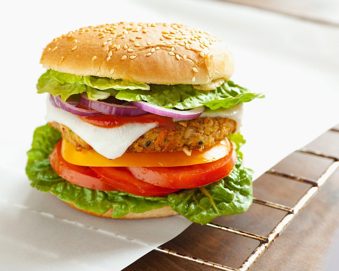 A vegetarian burger with a vegetable patty and goat's cheese, on grease-proof paper on a grill rack