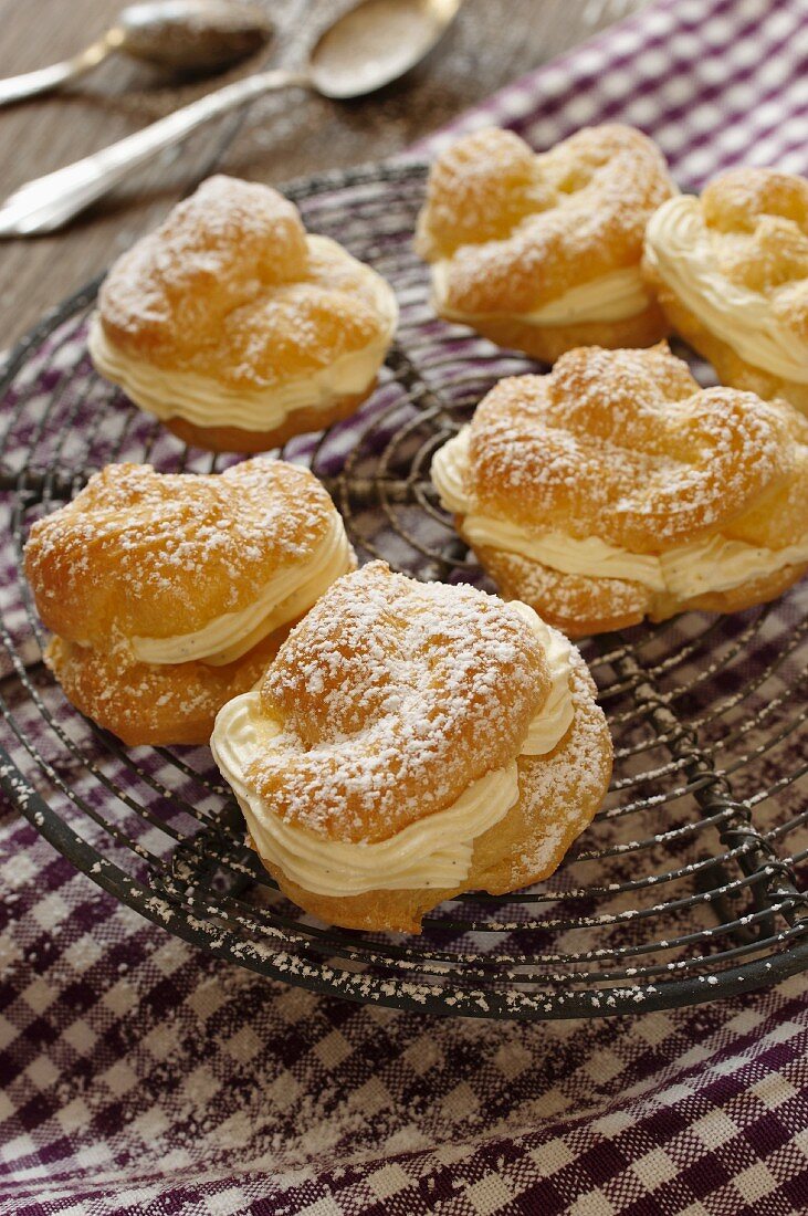 Profiteroles dusted with icing sugar, on a cooling rack