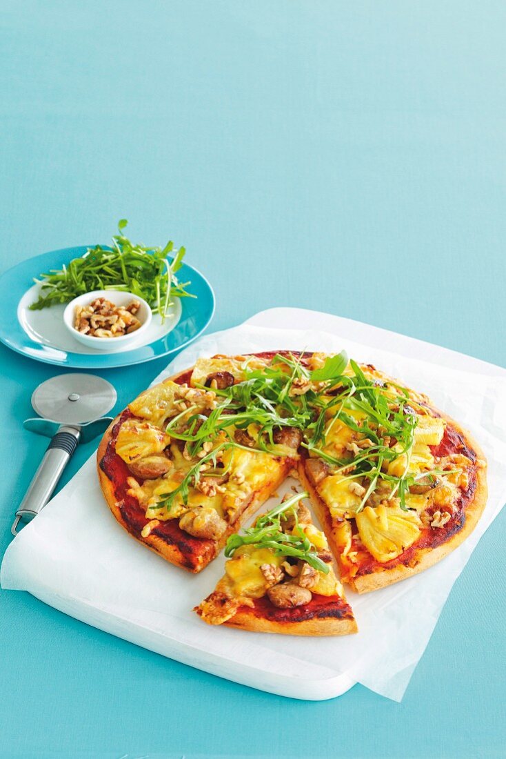 Pizza topped with caramelised pineapple, sausage bites, rocket and walnuts