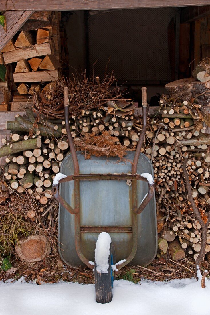 Wheelbarrow leaning against stacked firewood