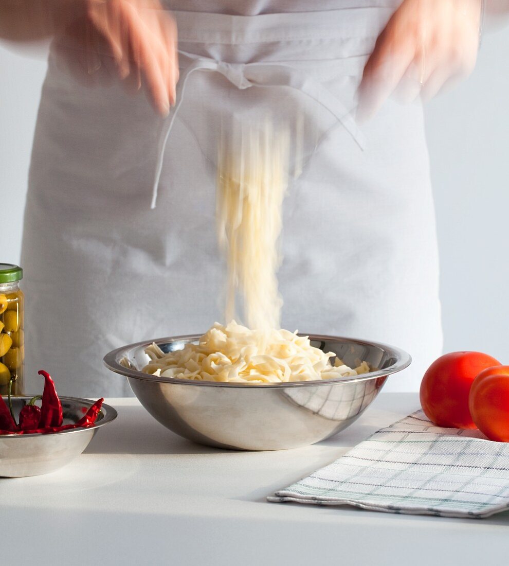 A woman mixing pasta in a bowl