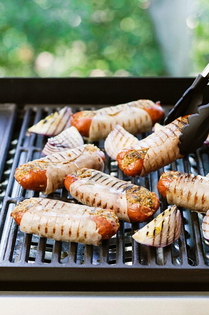 Stuffed sausages wrapped in ham on the barbecue