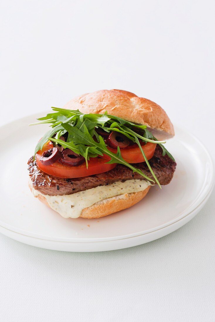 A burger with rump steak, tomatoes, olives and rocket (Italy)