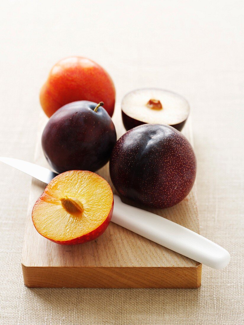 Fresh Plums on a Cutting Board; One Halved