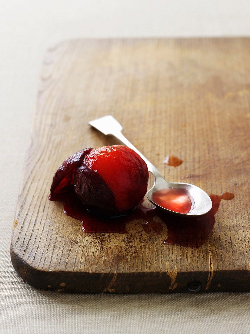 A poached plum with some juice on a chopping board