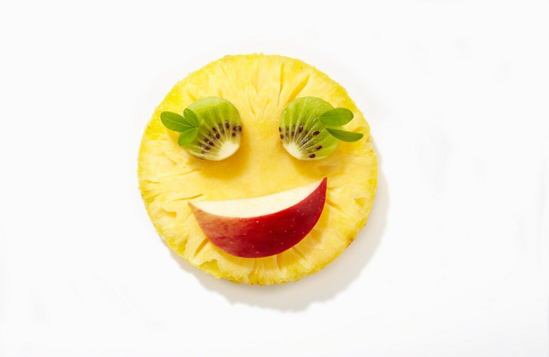 Lächelndes Obstgesicht aus Ananas, Kiwis und Apfel