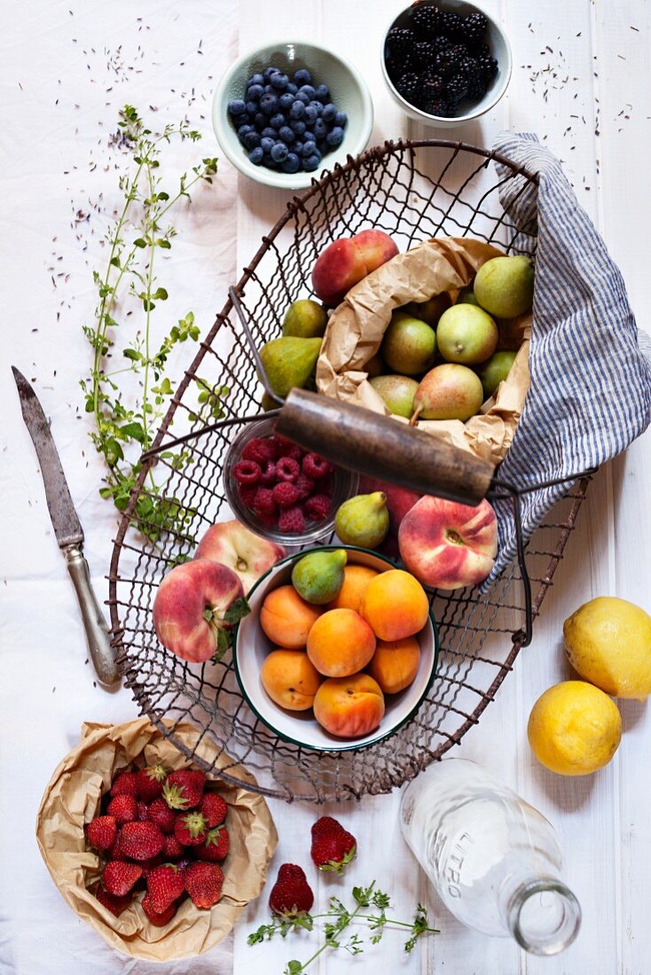 A still life of a wire basket with fresh summer fruits