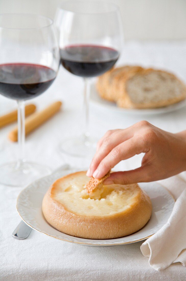 Hand dippt Brot in Torta del Casar (Schafskäse, Spanien)