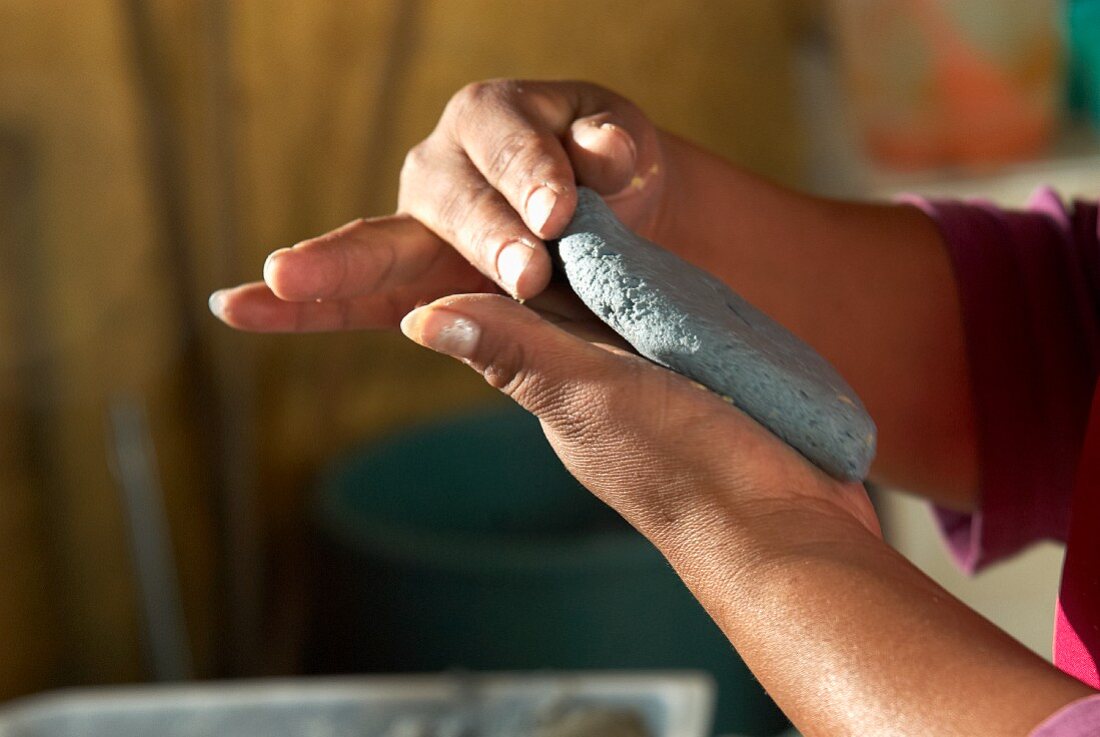 Hände formen Tlacoyo (ovale Maistortilla, Mexiko)