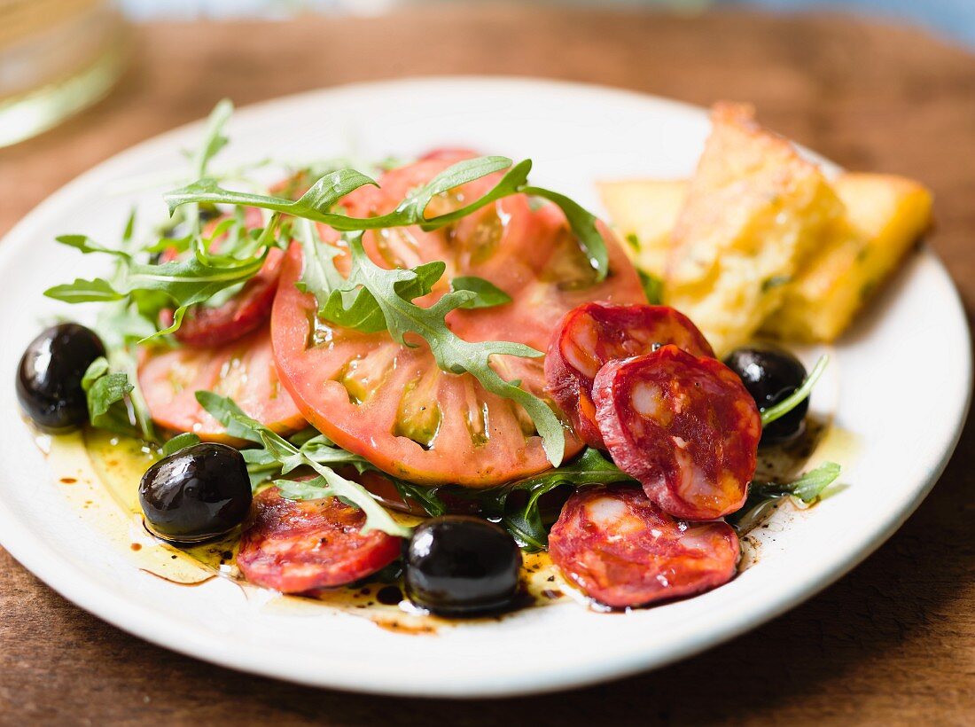 Tomatensalat mit Chorizo, Oliven, Rucola und Polentaecken