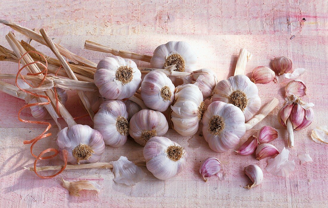 Several bulbs of garlic and cloves of garlic on pale wood