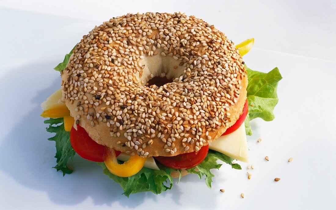 A sesame seed bagel filled with vegetables and cheese