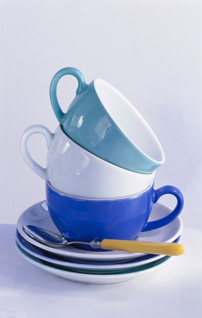 A stack of cups with saucers and a spoon