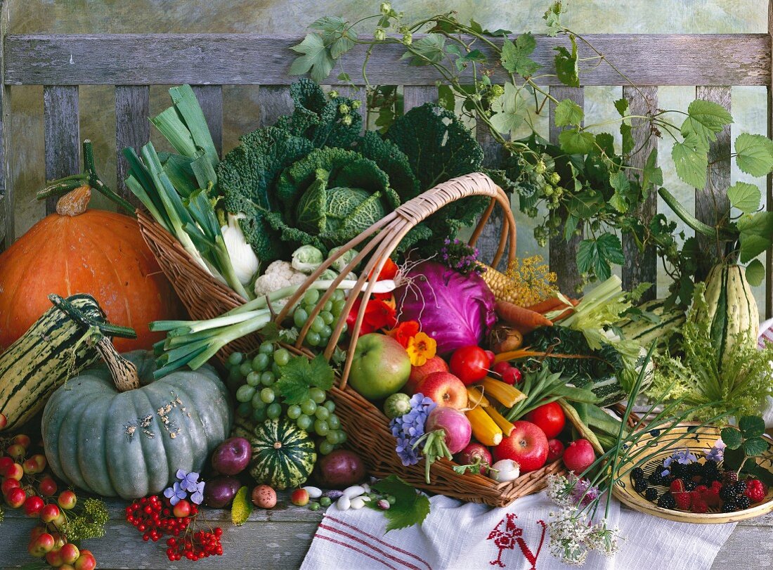 A basket of fruit and vegetables on a wooden bench