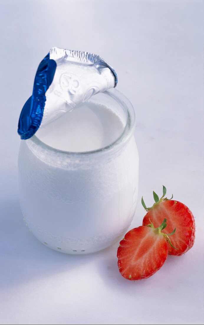 A jar of yoghurt and a halved strawberry