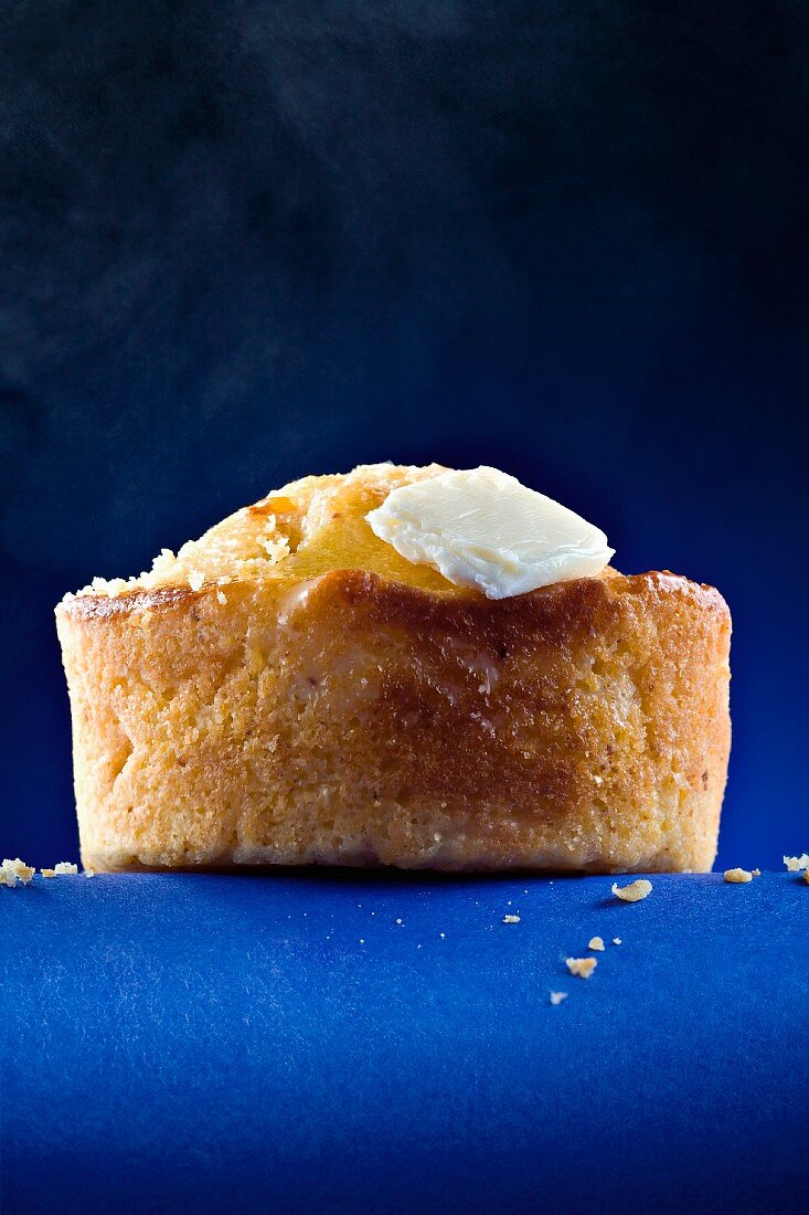 A Corn Muffin with Butter on Blue