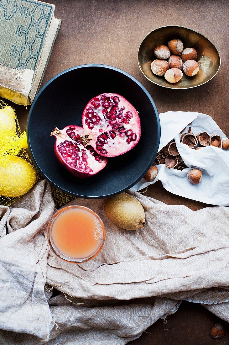 Stillleben mit Fruchtsaft, Granatapfel, Haselnüssen und Zitronen
