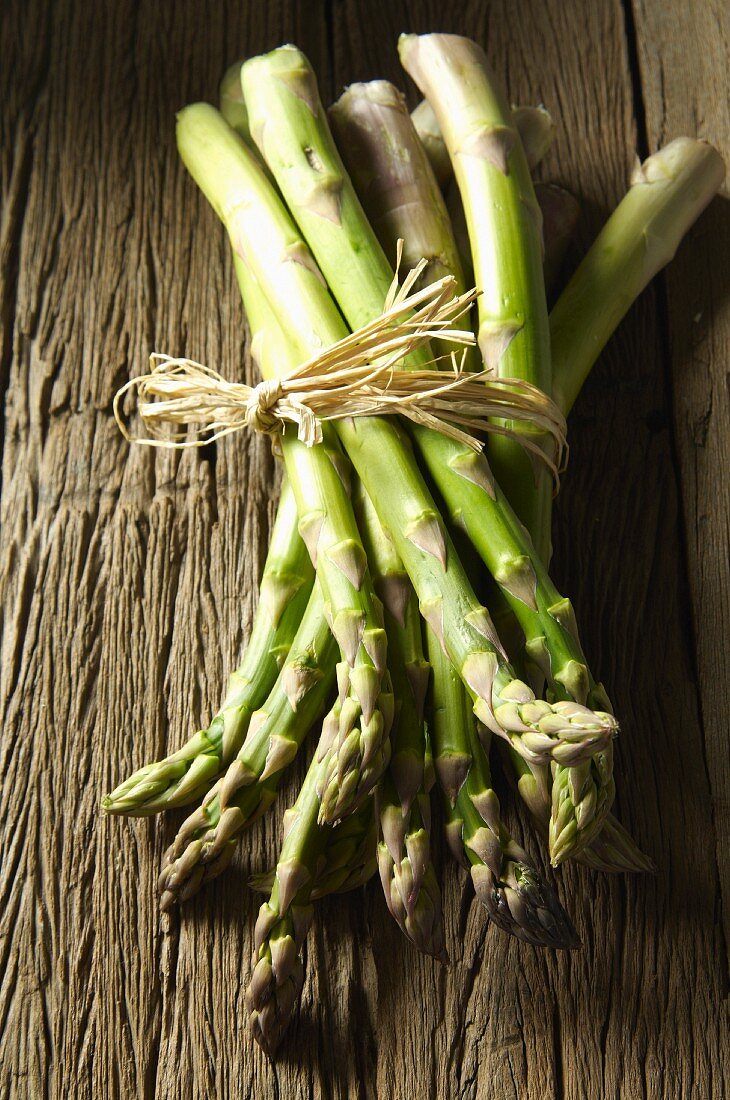 A bunch of green asparagus on a wooden surface