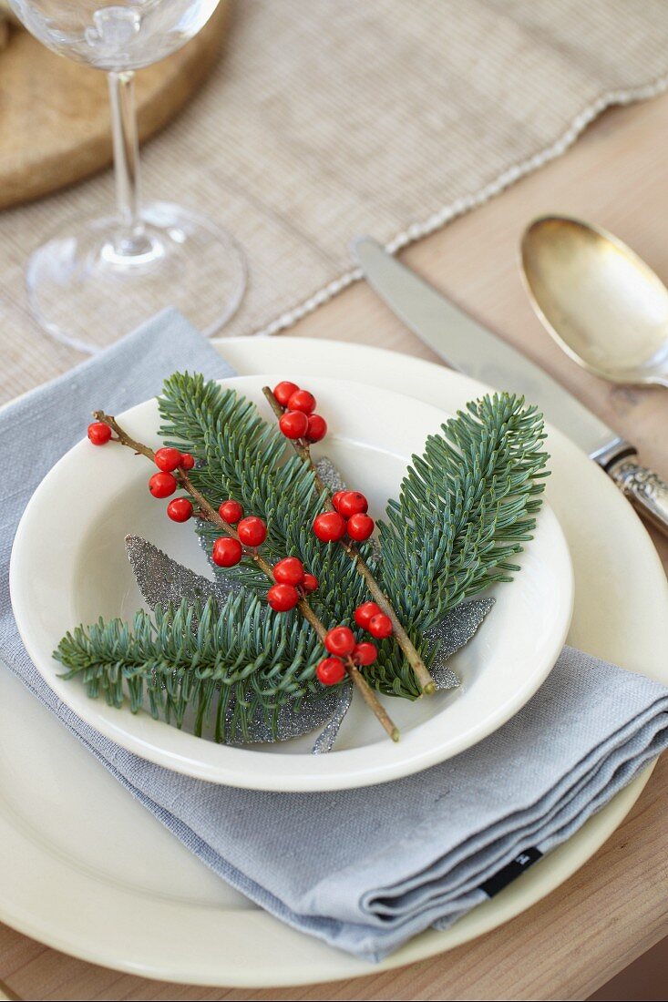 A Christmas place setting with fir branches and berries
