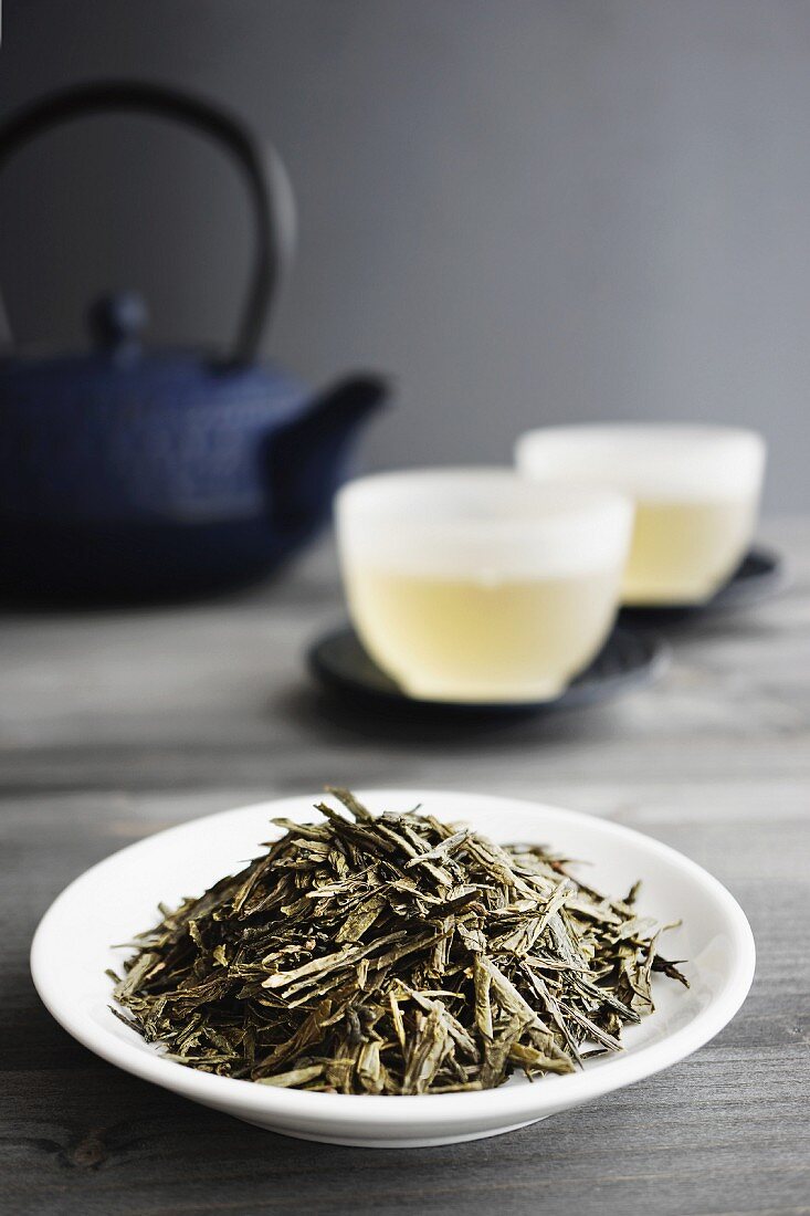 Zwei Tassen Grüntee, Teeblätter und japanische Teekanne