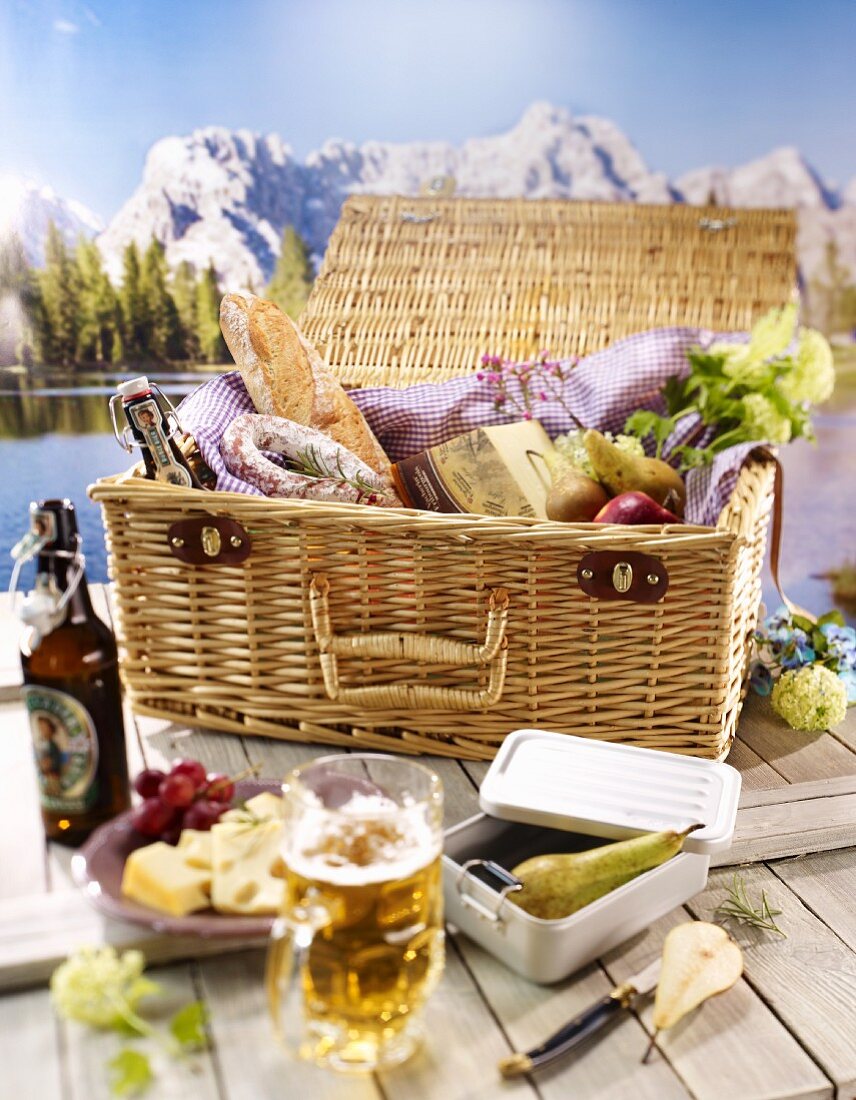 A table with a light meal and a picnic basket against a mountain view