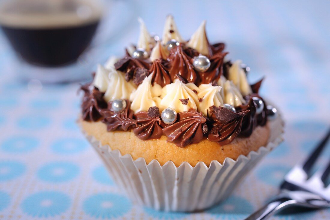 A cupcake with piped cream icing and silver balls