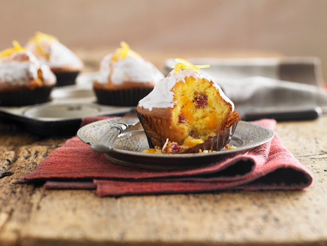 An orange and cranberry muffin with a bite missing